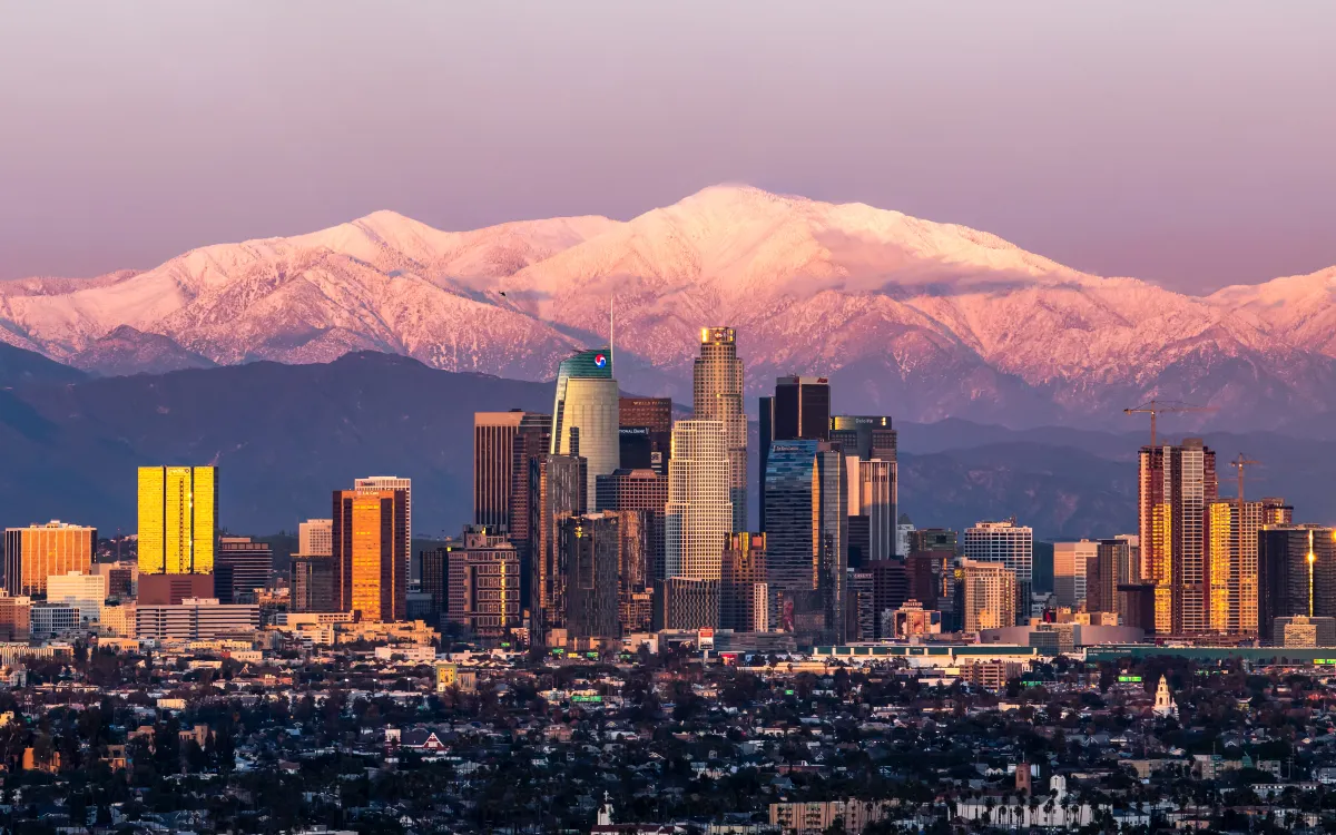 Downtown Los Angeles with snow-covered Mount Baldy behind the skyline at sunset